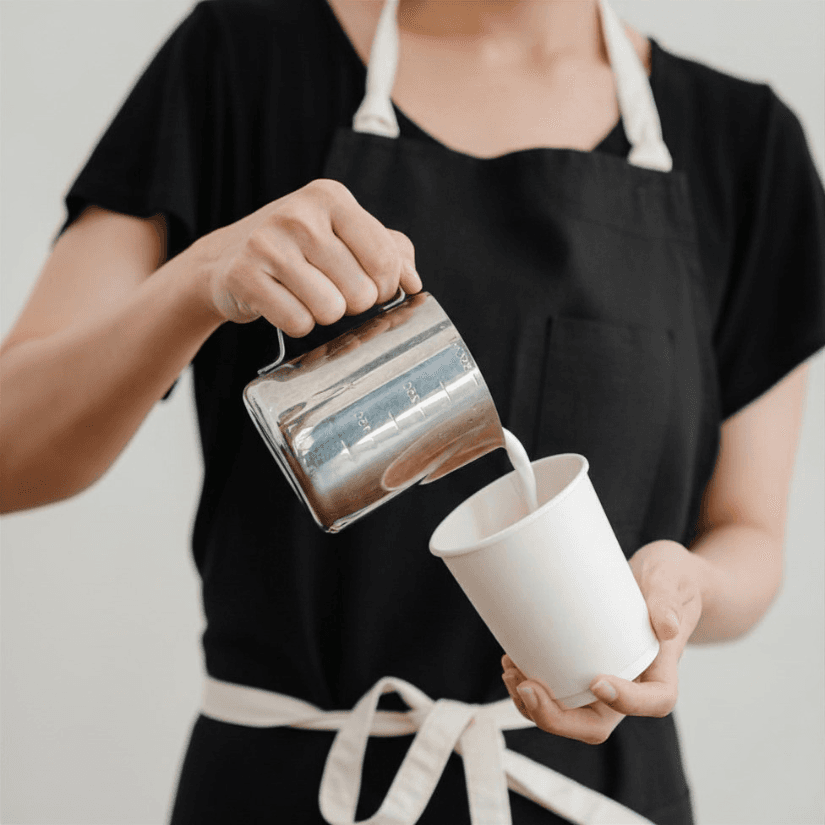 Barista in a black apron pouring a latte at a Cleveland Heights event